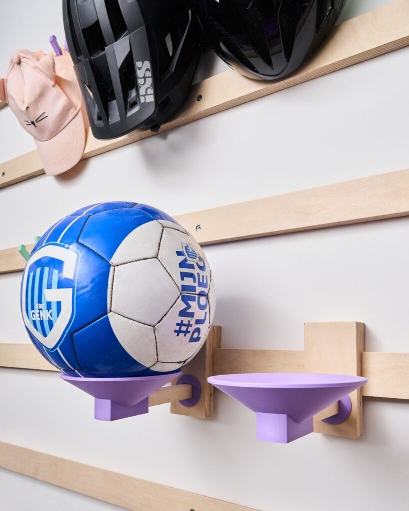 WandOrde modulair wandsysteem met paarse balhouders voor voetballen, fietshelmen en sportspullen in de inkomhal, berging of garage.