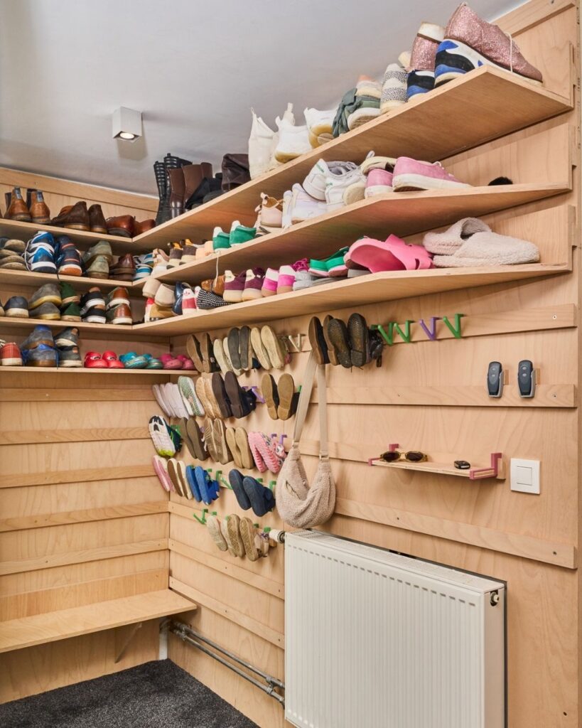 Modulair houten WandOrde wandsysteem in een inkomhal met schoenen, pantoffels, legplanken en ophanghaakjes.