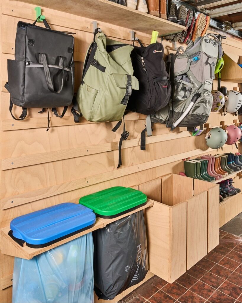 WandOrde wandsysteem in een garage met rugzakken, schoenen, laarzen, bakken en buitenspullen overzichtelijk aan de wand.