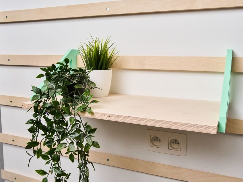 Houten legplank met groene planten aan een modulair WandOrde wandsysteem met mintgroene plankdragers