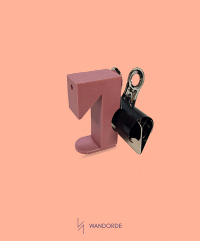 Zwarte klemhouder accessoire bevestigd op WandOrde wandsysteem tegen zalmkleurige achtergrond