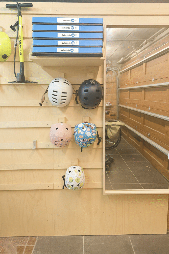 Modulair houten WandOrde-wandsysteem in een garage, met opbergvakken, fietspomp en meerdere fietshelmen netjes georganiseerd.