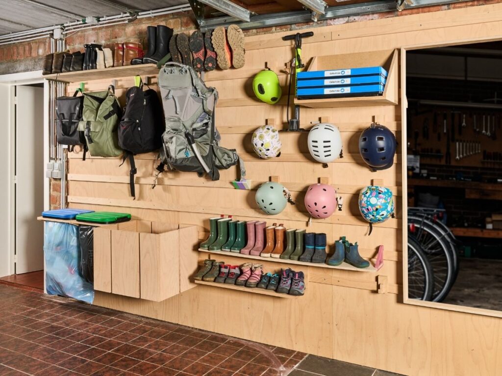 WandOrde modulair wandsysteem in garage met opbergruimte voor rugzakken, fietshelmen, laarzen, schoenen, step en buitenspullen.