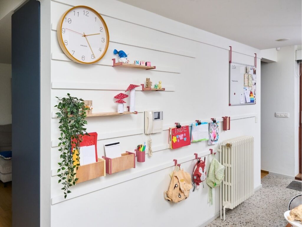WandOrde modulair wandsysteem met leggers, haakjes en opbergruimte voor tekeningen, boekentassen en kinderspullen.
